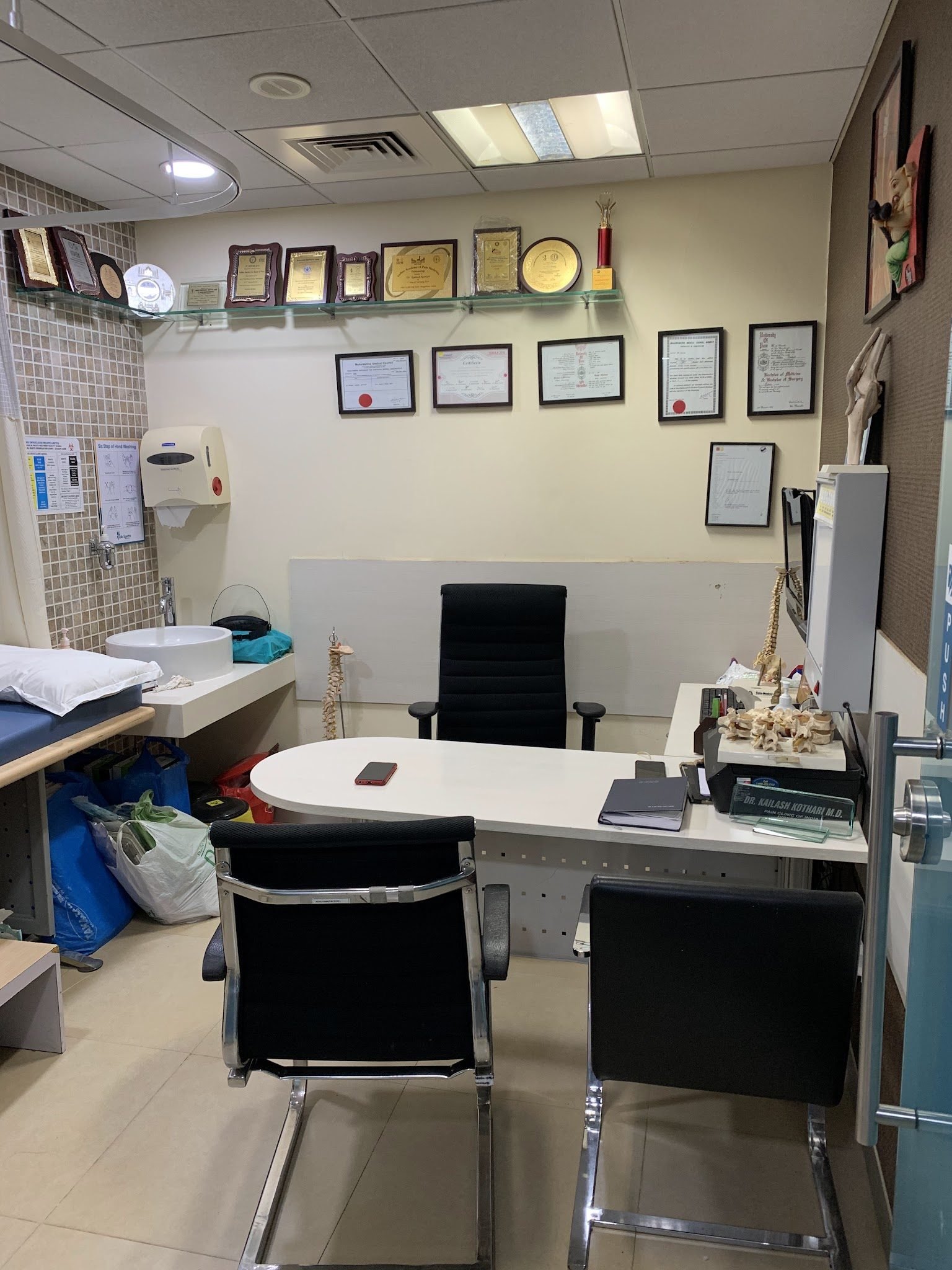 Consultation room at Pain Clinic of India with doctor credentials on the wall